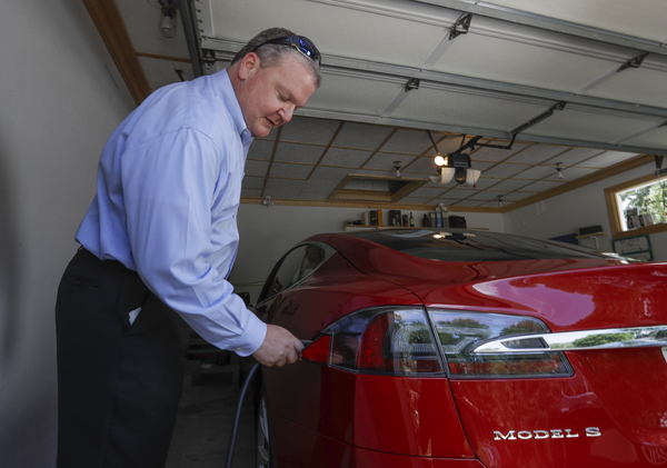 A man plugs in an electric Tesla sedan at his home in New Berlin, Wisconsin.