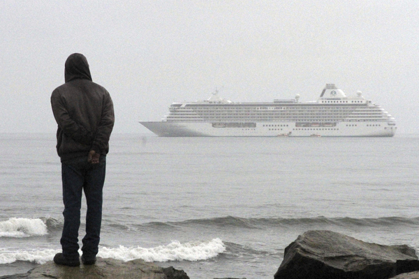 A man stands on the shore of the Bering Sea to watch the luxury cruise ship Crystal Serenity anchored just outside Nome, Alaska.