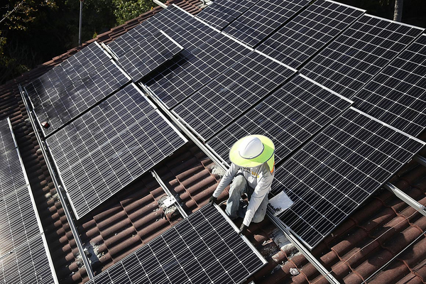 Worker installing rooftop solar panel.  