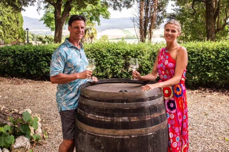 man and woman standing around wine barrel