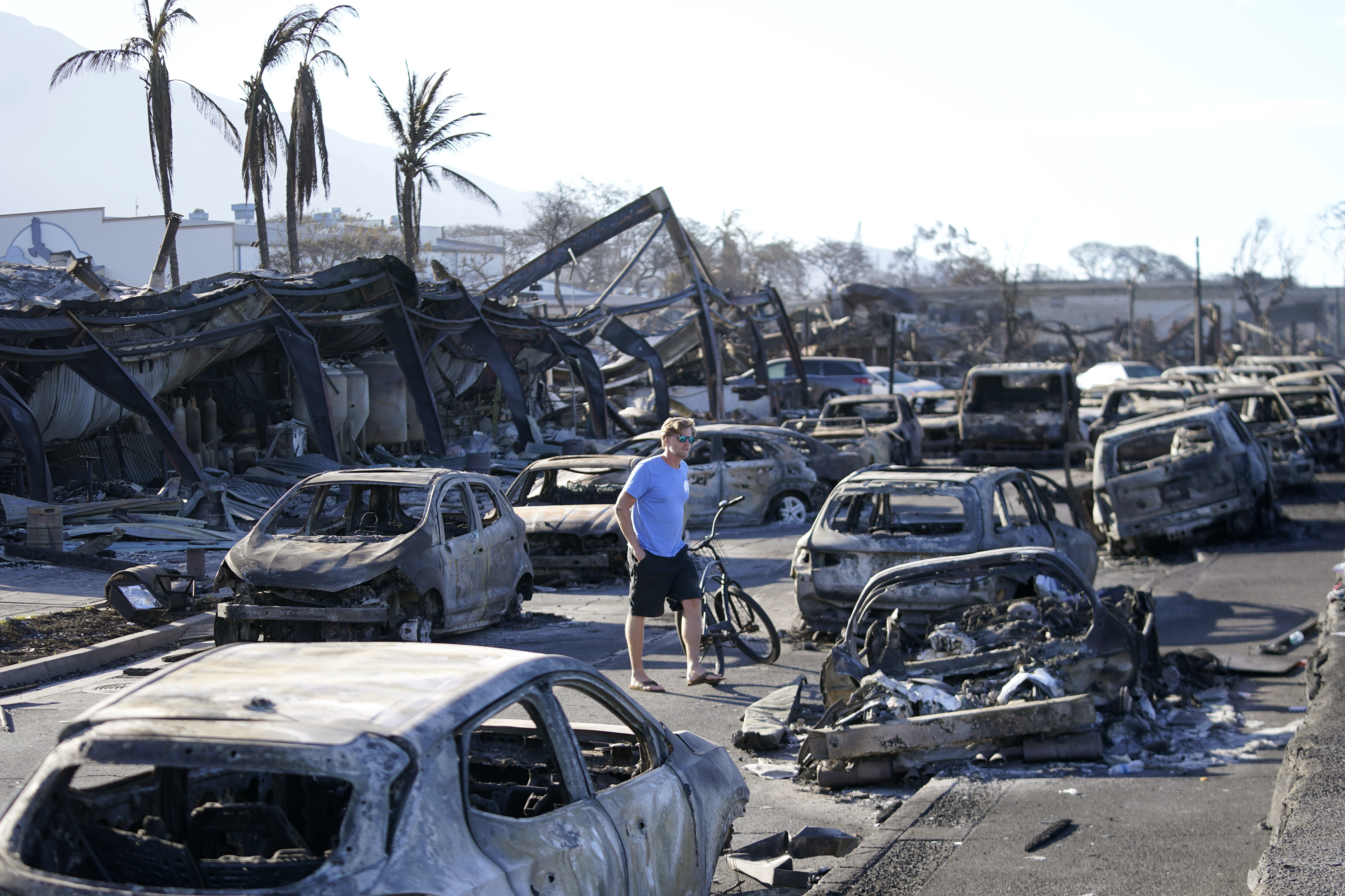 A man walks through wildfire wreckage in Lahaina.