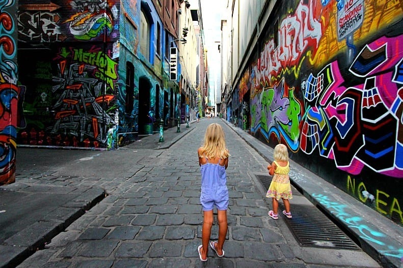 girls walking through an alleyway covered in graffiti
