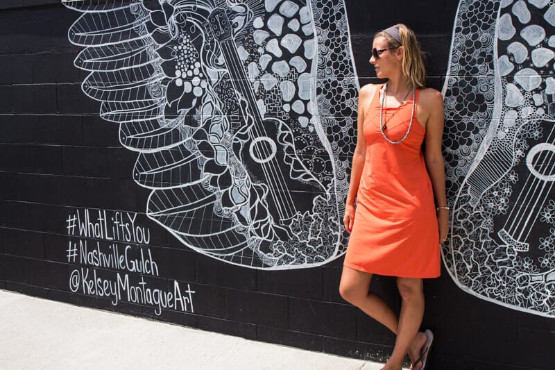 woman standing in front of a wall mural of wings