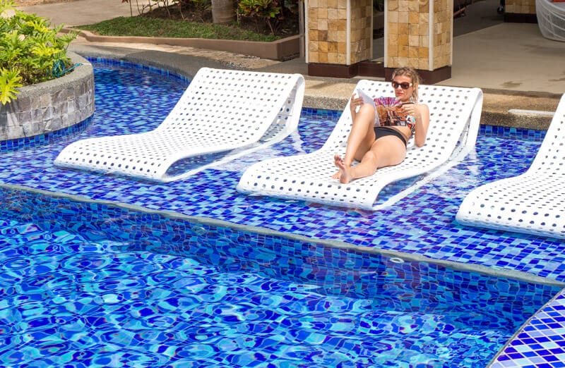 woman sitting on a lounge chair next to a pool
