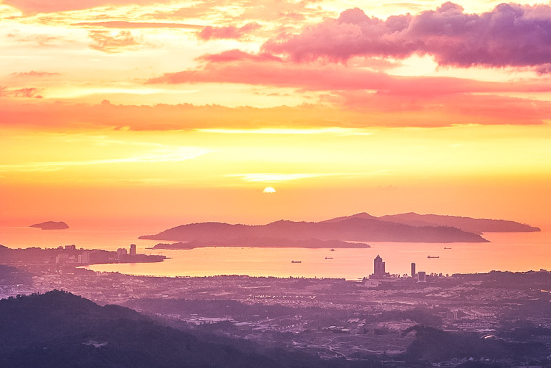 View of silhouette landscape with Kota Kinabalu city against islands at golden sunset. Sabah state, Malaysia.